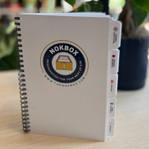 Notebook with Nokbox logo on a table with a plant in the background